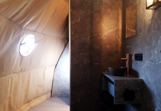 Vista interior del lodge Dome en Costa Kabrita, Países Bajos, con baño moderno y pared de tienda de campaña.