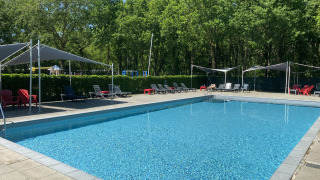 Piscina al aire libre con tumbonas y sombrillas en Holiday Park Duinhoeve, Brabante Septentrional, Países Bajos.