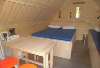 Interno del Kabouterhuisje al Vakantiepark 't Urkerbos nei Paesi Bassi, con arredamento in legno e letti.