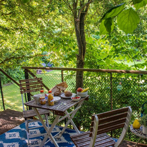 Desayuno servido en el balcón de una casa del árbol en Buytenplaets Suydersee, Países Bajos, entre vegetación.