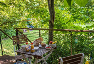 Desayuno servido en el balcón de una casa del árbol en Buytenplaets Suydersee, Países Bajos, entre vegetación.
