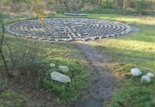 Stenlabyrint i en skov i nærheden af Vakantiepark De Luttenberg, Overijssel, Holland, med en grøn græsplæne.