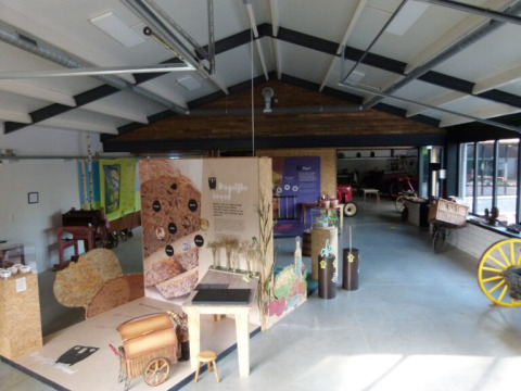 Tentoonstellingsruimte met landbouwwagens en infoborden in Vakantiepark De Luttenberg, Nederland.