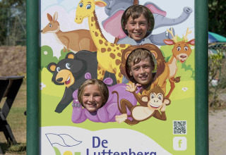 Tre børn poserer med hoveder gennem et skilt med dyremotiver ved Vakantiepark De Luttenberg i Holland.