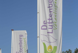 Flag foran De Luttenberg Feriepark i Overijssel, Holland, vejr med blå himmel og grøn baggrund.
