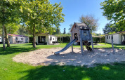 Legeplads med rutsjebane og sand omgivet af ferieboliger i solrigt feriepark De Luttenberg, Overijssel.