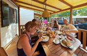 Familia desayuna junta en la terraza de SunLodge Maple en Camping Bella Italia, Italia, en un ambiente relajado.