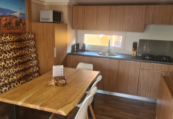 Cucina moderna e zona pranzo al SunLodge Babul con arredamento in legno, seduta leopardata e arte safari.
