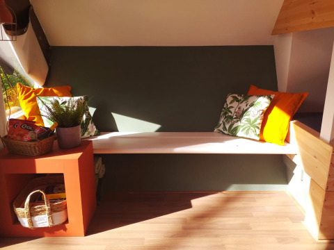 Knusse bank met kussens in tiny house Trekkershut op Buytenplaets Suydersee, Nederland, zonlicht.