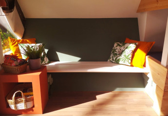 Banco acogedor con cojines en la tiny house Trekkershut de Buytenplaets Suydersee, Países Bajos, luz solar.