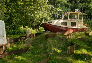 Kajuitboot aan lodge Buytenplaets Suydersee, Nederland, op een grasheuvel in een bosrijke omgeving.