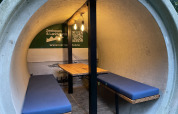 Interior de una cabaña redonda de hormigón con bancos y mesa en Kajuitboot, Buytenplaets Suydersee, Países Bajos.