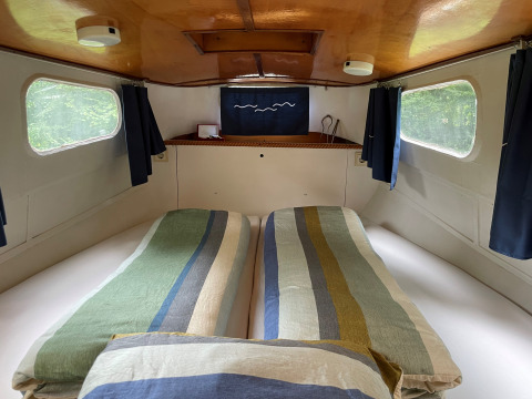 Acogedor dormitorio en la cabaña Kajuitboot en Buytenplaets Suydersee, Países Bajos, con camas gemelas.