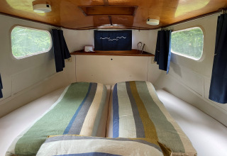 Acogedor dormitorio en la cabaña Kajuitboot en Buytenplaets Suydersee, Países Bajos, con camas gemelas.