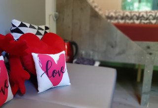 Acogedor interior de la tiny house Pipo Love en Buytenplaets Suydersee, Países Bajos, con cojines de corazón.