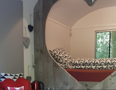 Acogedor rincón para dormir con decoración de corazones en la tiny house Pipo Love de Buytenplaets Suydersee, Países Bajos.