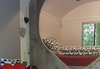 Accogliente angolo notte con decorazioni a cuore nella tiny house Pipo Love a Buytenplaets Suydersee, Paesi Bassi.
