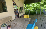 Terraza exterior de una tienda safari en Buytenplaets Suydersee con mesa de madera, sillas de colores y plantas.