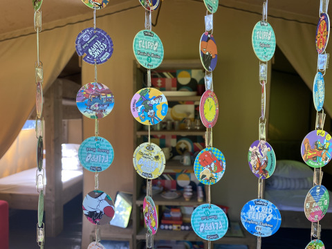 Interior view of a safari tent at Buytenplaets Suydersee, Netherlands, with colorful pogs hanging as a curtain.