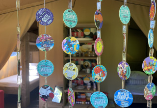 Intérieur d'une tente safari à Buytenplaets Suydersee, Pays-Bas, avec des pogs colorés suspendus en rideau.