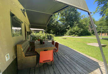 Udendørs siddeområde med træbord og stole ved safari-telt på Buytenplaets Suydersee, Holland.