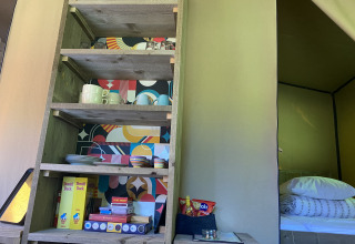 Scaffale da cucina con stoviglie, lattine di Donald Duck e giochi in tenda safari a Buytenplaets Suydersee, Olanda.