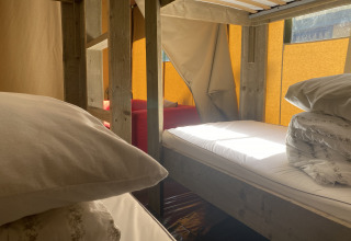 Vista interna di una tenda safari a Buytenplaets Suydersee nei Paesi Bassi con letti a castello e luce solare.