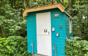Una pequeña cabaña turquesa con puerta blanca en el bosque en Buytenplaets Suydersee, Países Bajos.