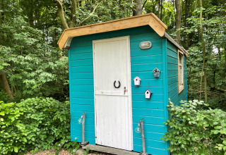 Ein kleines türkisfarbenes Haus mit weißer Tür im Wald bei Buytenplaets Suydersee, Niederlande.