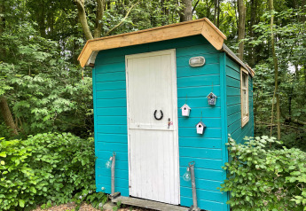 Una pequeña cabaña turquesa con puerta blanca en el bosque en Buytenplaets Suydersee, Países Bajos.