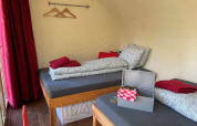 To enkeltsenge og røde gardiner i Boomhut Family træhus på Buytenplaets Suydersee, Holland.