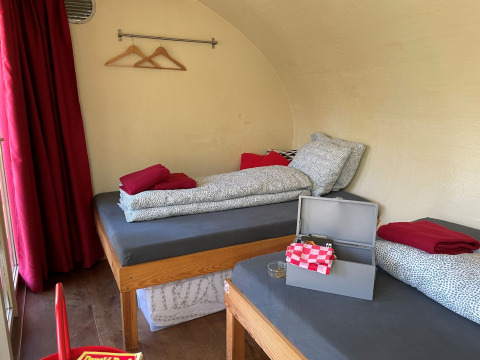 Two single beds and red curtains in Boomhut Family tree house at Buytenplaets Suydersee, Netherlands.