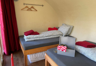 Two single beds and red curtains in Boomhut Family tree house at Buytenplaets Suydersee, Netherlands.
