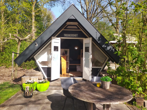 Pequeña casa triangular Trekkershut en Buytenplaets Suydersee, Países Bajos, rodeada de árboles y naturaleza.