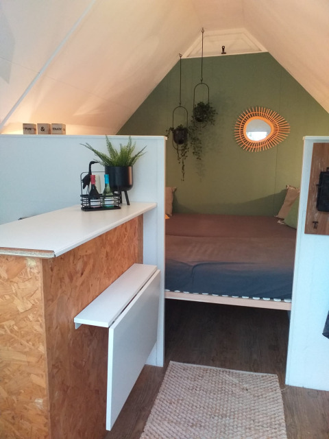 Interior moderno de casa pequeña en Trekkershut, Buytenplaets Suydersee, Países Bajos, con cama y plantas colgantes.