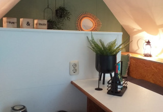 Angolo mansardato luminoso e accogliente in una tiny house Trekkershut con scrivania, piante e bollitore nei Paesi Bassi.
