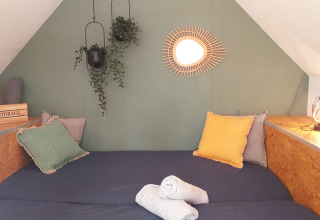 Espace nuit confortable dans une tiny house Trekkershut à Buytenplaets Suydersee, Pays-Bas, avec plantes.