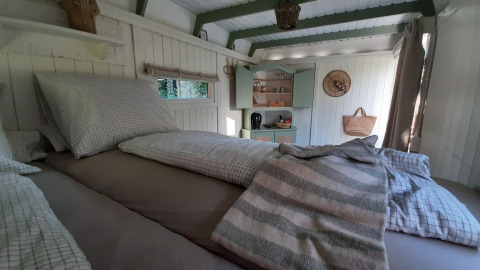 Gemütliches Schlafzimmer in der Pipo Maison Lodge mit kariertem Bettzeug und Küchenecke aus Holz.