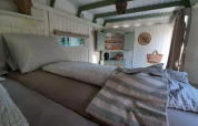Sfeervolle slaapkamer in de Pipo Maison lodge met geruit beddengoed en houten keukentje.