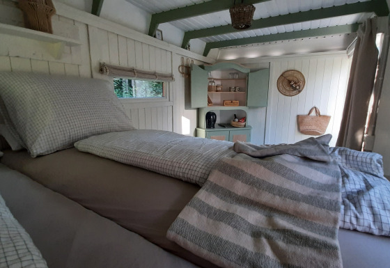 Acogedor dormitorio en la cabaña Pipo Maison con ropa de cama a cuadros y rincón de cocina integrado.