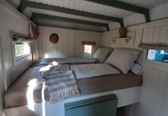 Knusse, lichte slaapkamer met ramen in de Pipo Maison-lodge bij Buytenplaets Suydersee in Nederland.