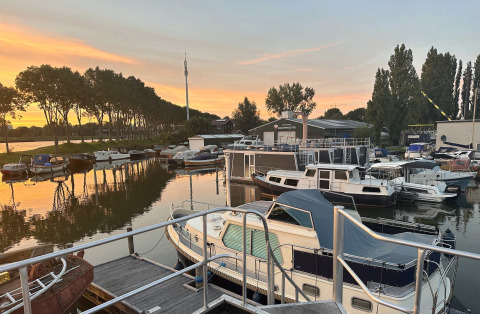 Boten aangemeerd aan het Marina Parcs Amsterdam vakantiepark in Noord-Holland bij zonsondergang.