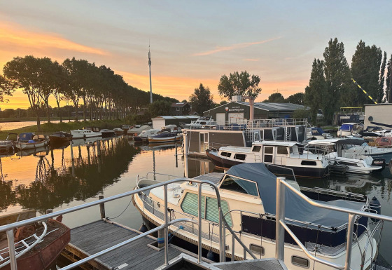 Boote liegen am Steg des Marina Parcs Amsterdam in Nordholland, Niederlande, bei Sonnenuntergang.