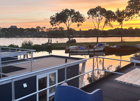 Vista del atardecer con casas flotantes y barcos en Marina Parcs Amsterdam, parque vacacional en Holanda Norte.