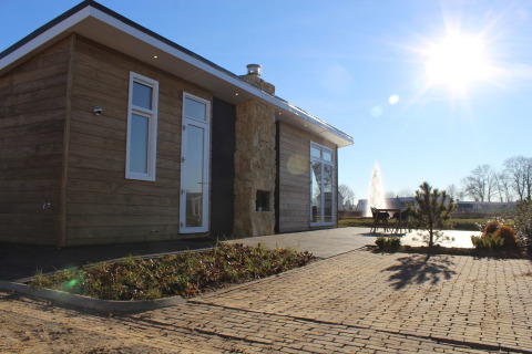 Moderna cabaña en Resort Mooi Bemelen, Países Bajos, con terraza, sol radiante y fuente cercana.