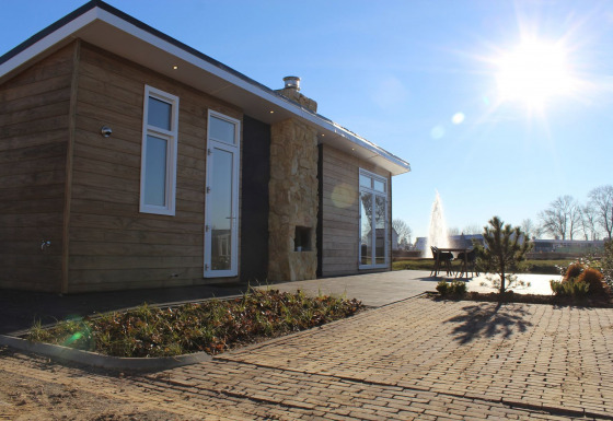 Moderna cabaña en Resort Mooi Bemelen, Países Bajos, con terraza, sol radiante y fuente cercana.