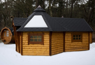 Finse Kota tiny house ved Costa Kabrita i Nederlandene, omgivet af sne og skov, set udefra.