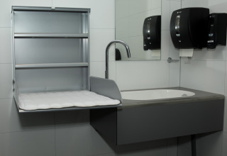 Restroom with baby changing station, sink, mirror, paper towel and soap dispenser at Costa Kabrita.