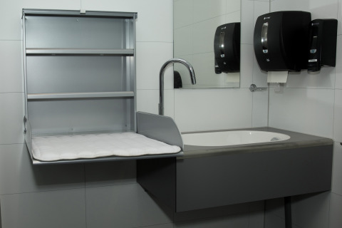 Restroom with baby changing station, sink, mirror, paper towel and soap dispenser at Costa Kabrita.