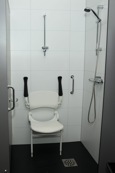 Ducha accesible con silla y barras de apoyo en una casa vacacional de Costa Kabrita, Brabante Septentrional, Países Bajos.